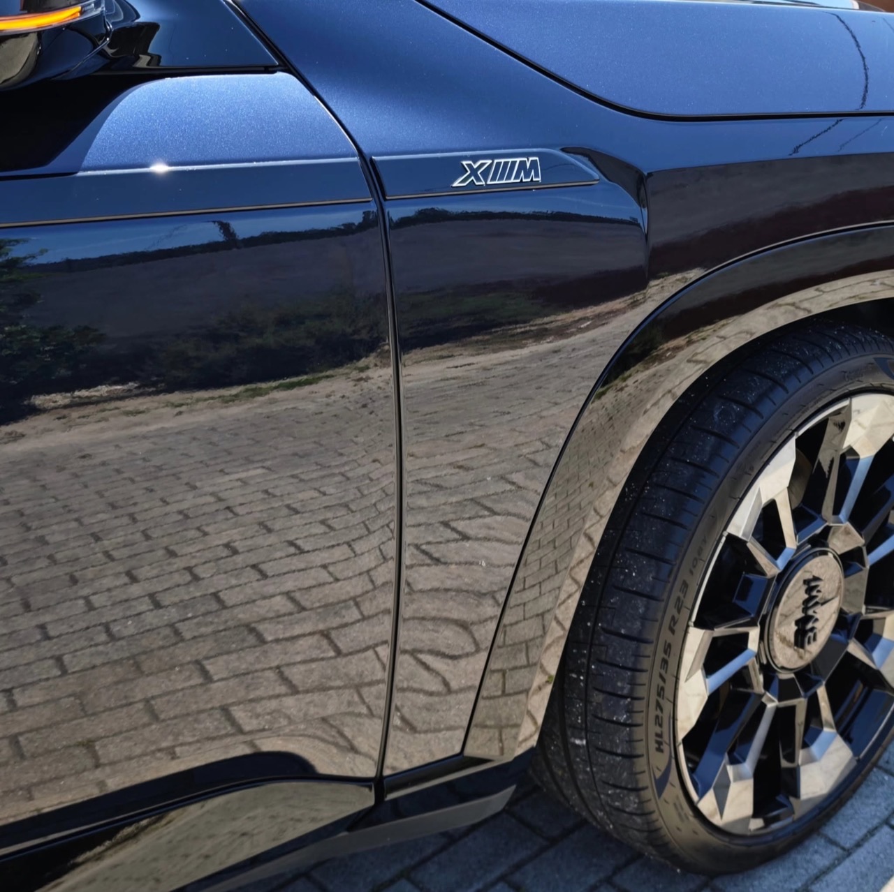 Lateral traseira do BMW XM preto, reflexos nítidos na pintura.